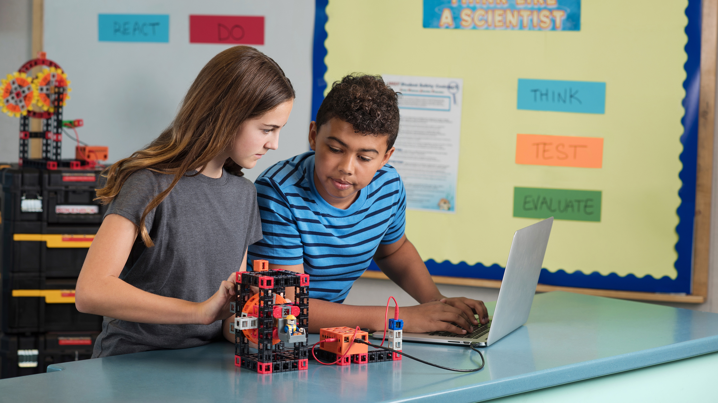 Image of two students using a computer to control a machine from the STEM kit"