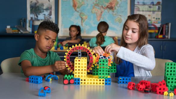 Two students building a interlocking gear machine with the Kid Spark STEM program kit
